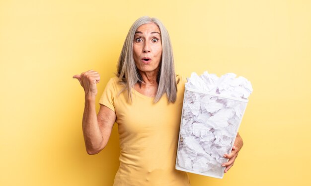 Hübsche Frau mittleren Alters, die ungläubig erstaunt aussieht. Papierkugeln Ausfallkonzept