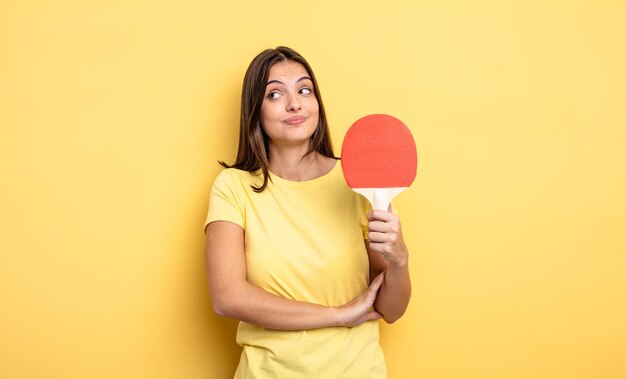 Hübsche Frau zuckt mit den Schultern, fühlt sich verwirrt und unsicher. Ping-Pong-Konzept