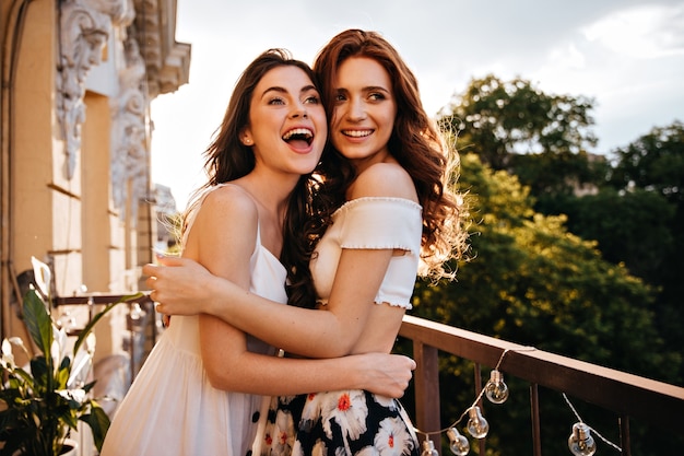 Hübsche Frauen in Sommeroutfits lächeln auf der Terrasse