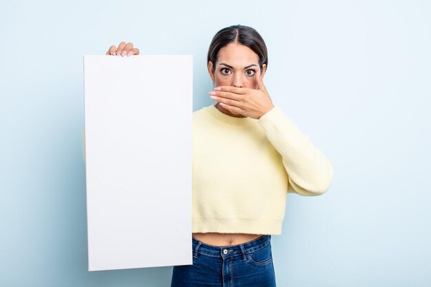 Foto hübsche hispanische frau, die den mund mit den händen mit einem schockierten bedeckt. leerzeichenkonzept