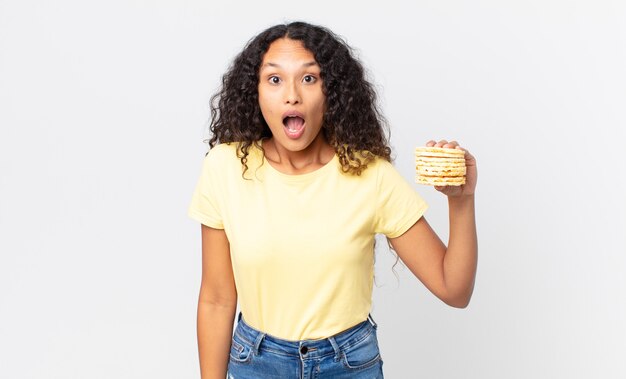 Hübsche hispanische Frau, die einen Reisdiätkuchen hält