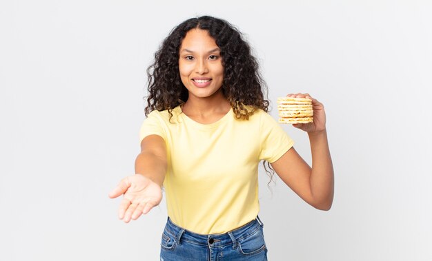 Hübsche hispanische Frau, die einen Reisdiätkuchen hält