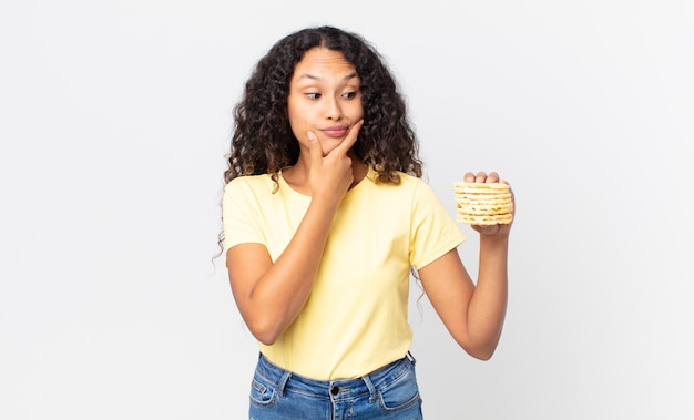 Hübsche hispanische Frau, die einen Reisdiätkuchen hält