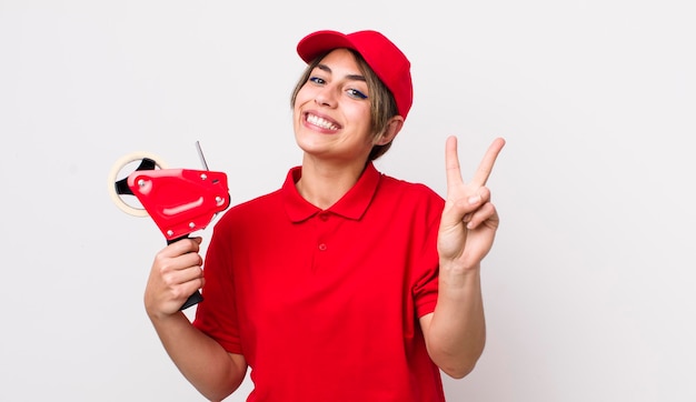 Hübsche hispanische Frau, die lächelt und freundlich aussieht und das Packerkonzept Nummer zwei zeigt