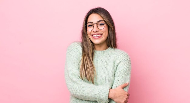 Hübsche hispanische Frau, die schüchtern und fröhlich mit einer freundlichen und positiven, aber unsicheren Haltung lacht