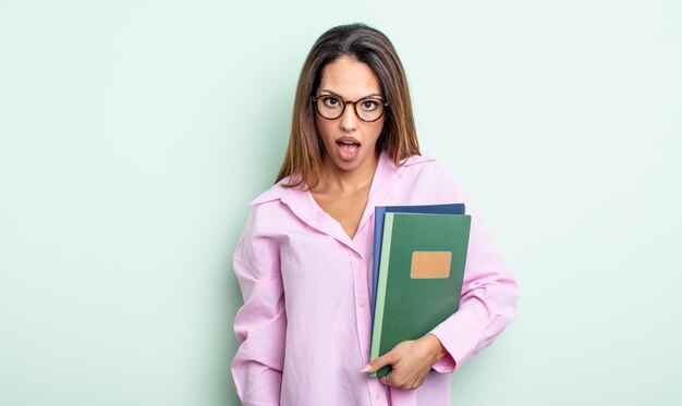 Hübsche hispanische Frau, die sehr schockiert oder überrascht aussieht. Notebook-Konzept