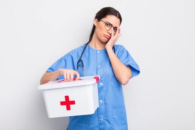 Foto hübsche hispanische frau, die sich nach einem ermüdenden gelangweilt, frustriert und schläfrig fühlt. krankenschwester und erste-hilfe-kasten