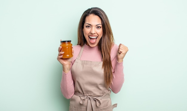 Hübsche hispanische Frau, die sich schockiert fühlt, lacht und den Erfolg feiert. Pfirsichmarmelade Konzept