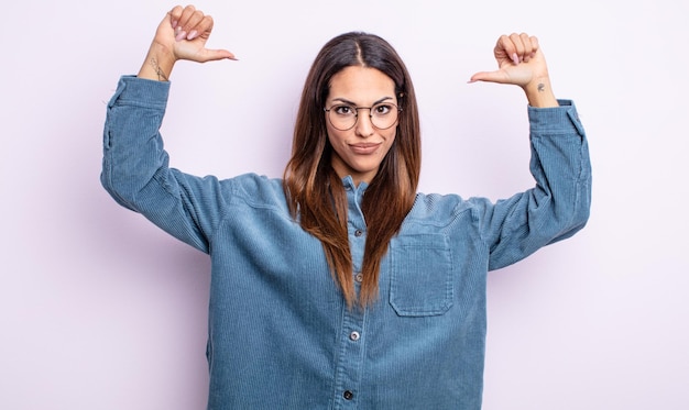 Hübsche hispanische Frau, die sich stolz, arrogant und selbstbewusst fühlt, zufrieden und erfolgreich aussieht und auf sich selbst zeigt