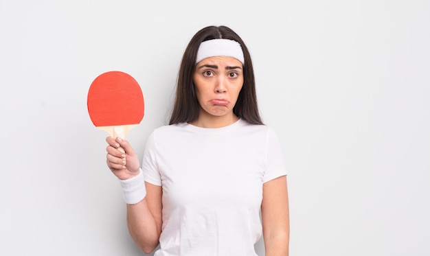 Hübsche hispanische Frau, die sich traurig und weinerlich fühlt, mit einem unglücklichen Blick und Weinen. Ping-Pong-Konzept