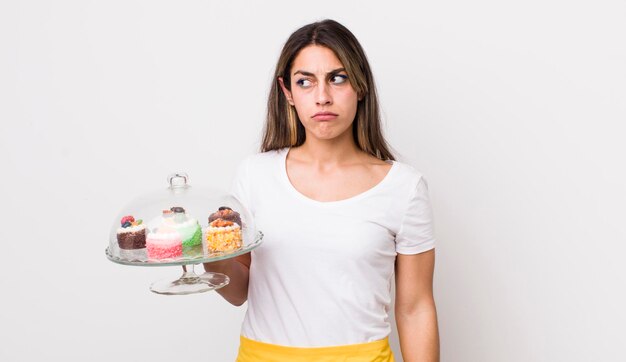 Foto hübsche hispanische frau, die sich traurig, verärgert oder wütend fühlt und auf das konzept der hausgemachten kuchen blickt