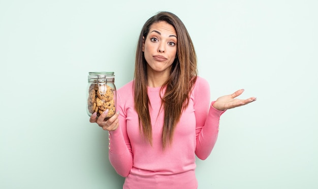 Hübsche hispanische Frau, die sich verwirrt und verwirrt fühlt und zweifelt. Cookies-Konzept