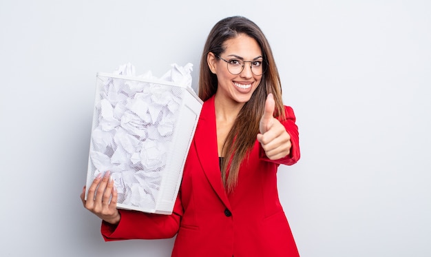 Hübsche hispanische Frau, die stolz ist und positiv mit Daumen nach oben lächelt. Papierkugeln Ausfallkonzept