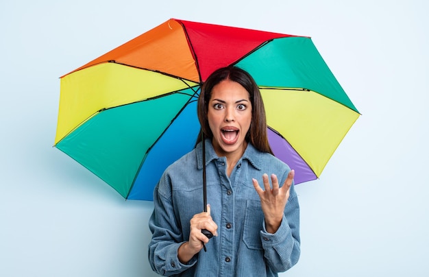 Hübsche hispanische Frau, die wütend, genervt und frustriert aussieht. Regenschirm-Konzept