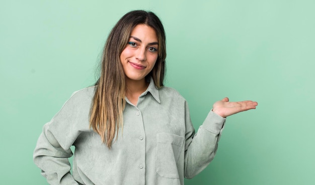 Hübsche hispanische Frau lächelt, fühlt sich zuversichtlich, erfolgreich und glücklich und zeigt Konzept oder Idee auf Kopienraum auf der Seite