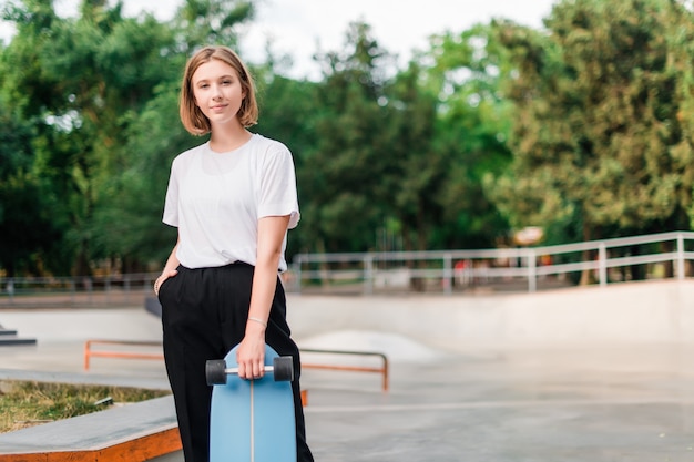 Hübsche Jugendliche mit Skateboard im Rochenpark