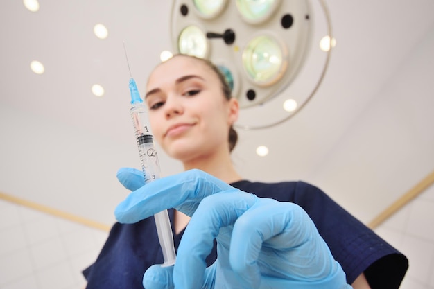 Foto hübsche junge ärztin im op-anzug mit blauen gummihandschuhen vor dem hintergrund einer operation