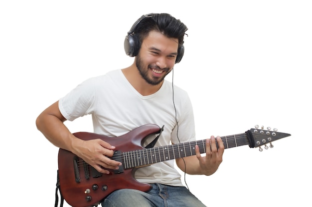 Hübsche junge asiatische Männer, die Gitarre spielen und hören Musik mit Kopfhörern, undeutlichem und Weichzeichnung