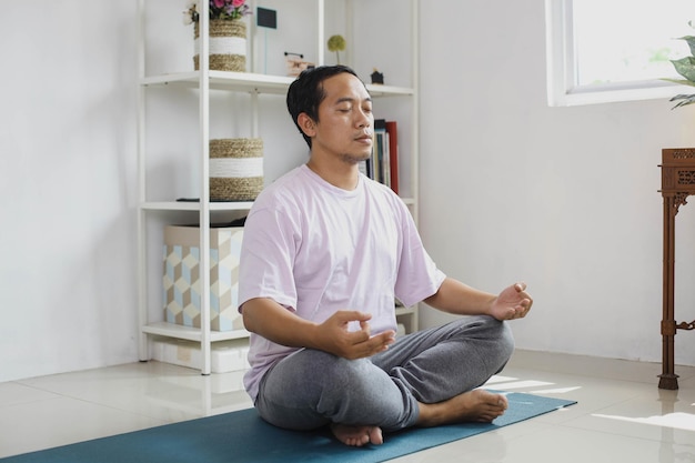 Hübsche junge asiatische Mannmeditation zu Hause