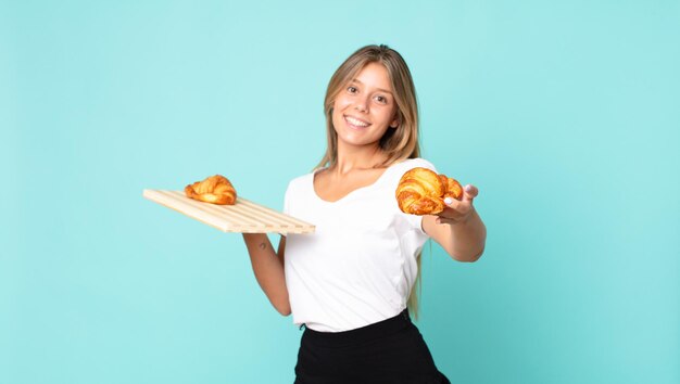 Hübsche junge blonde Frau mit einem Croissant-Tablett