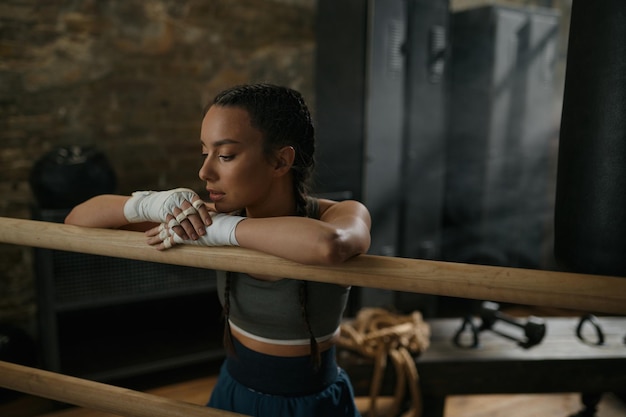 Hübsche junge Boxerin, die sich am Ring ausruht und zum Training bereit ist