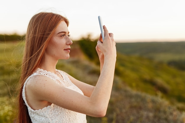 Hübsche junge Dame, die Fotos der Landschaft macht