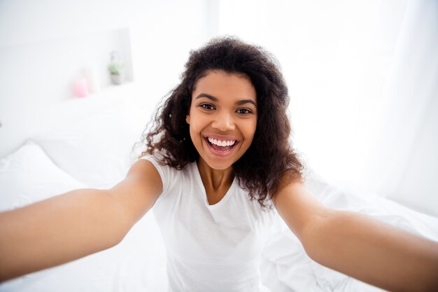 Hübsche junge Dame, die im Bett sitzt