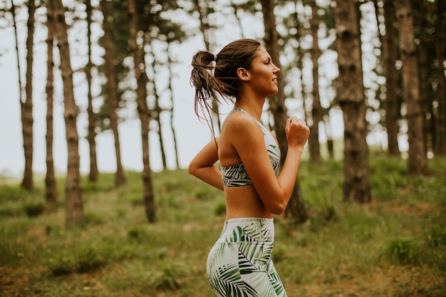 Hübsche junge Fitnessfrau, die am Waldweg läuft