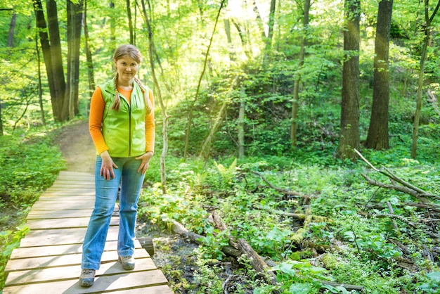 Hübsche junge Frau auf Brücke im grünen sonnigen Wald