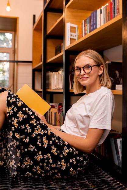 Hübsche junge Frau, die an der Bibliothek aufwirft