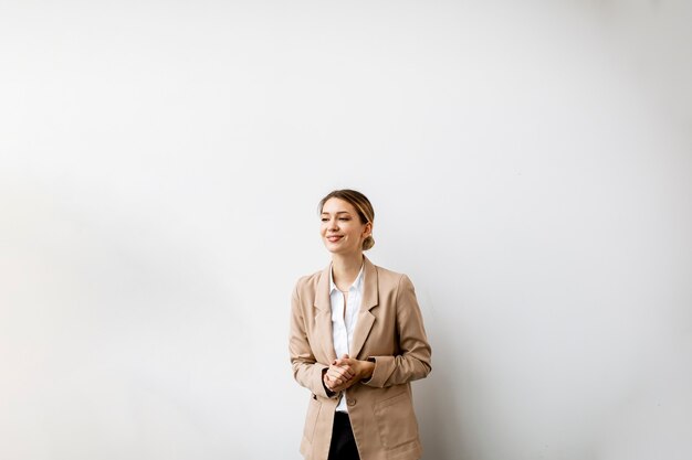 Hübsche junge Frau, die an der weißen Wand im modernen Büro steht