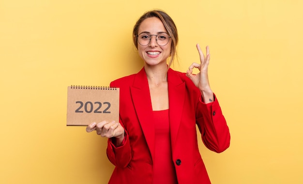 Hübsche junge Frau, die einen Kalender 2022 hält