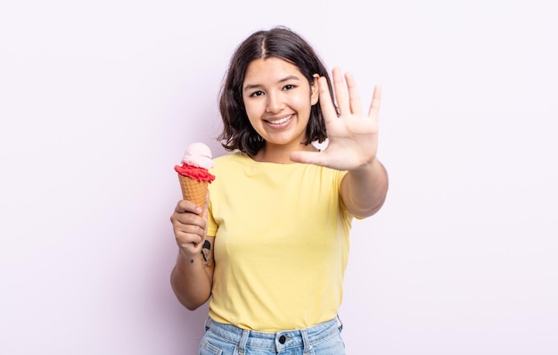 Hübsche junge Frau, die freundlich lächelt und aussieht und Nummer fünf zeigt. Eiskonzept