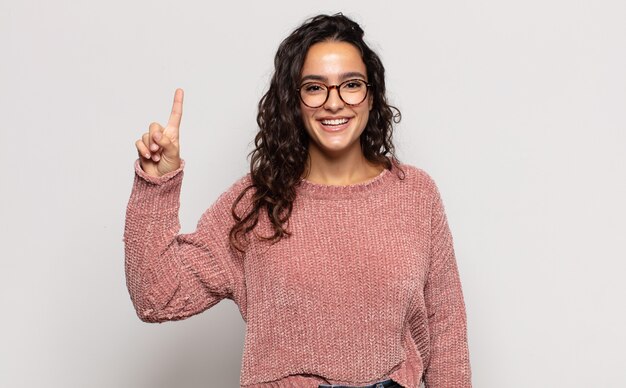 Hübsche junge Frau, die fröhlich und glücklich lächelt und mit einer Hand nach oben zeigt, um Raum zu kopieren