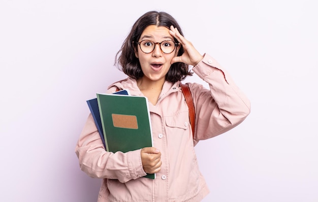 Hübsche junge Frau, die glücklich, erstaunt und überrascht aussieht, Studentin mit Buchkonzept