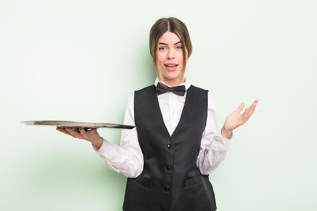 Hübsche junge Frau, die glücklich überrascht ist, eine Lösung oder einen Ideenkellner mit einem Tablettkonzept zu realisieren