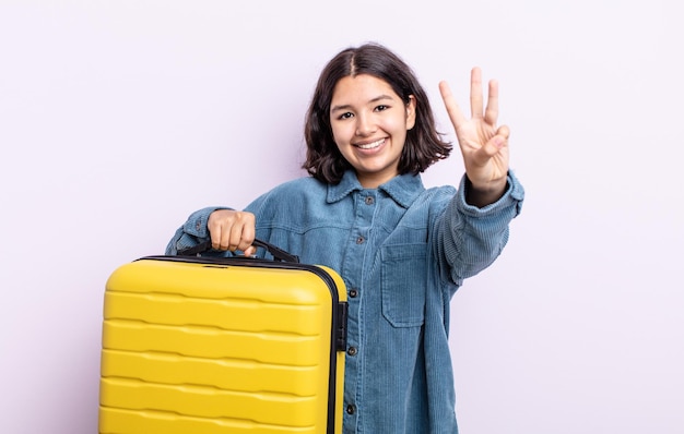 Hübsche junge Frau, die lächelt und freundlich aussieht und das Reisekofferkonzept Nummer drei zeigt