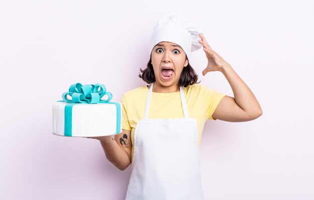 Hübsche junge Frau, die mit den Händen in die Luft schreit. Koch kocht einen Kuchen