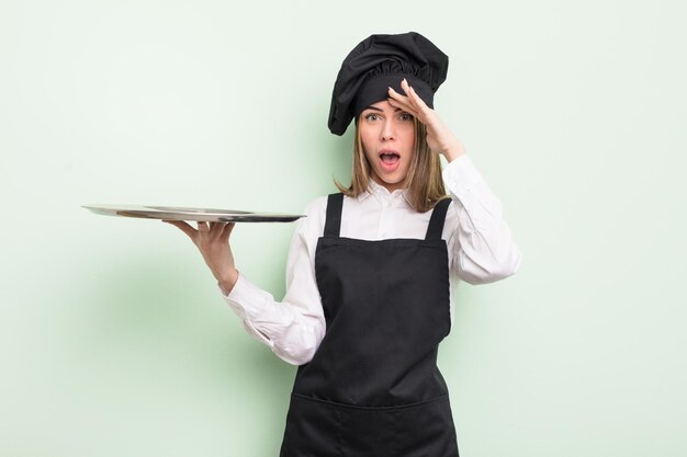 Hübsche junge Frau, die mit einem Tablettkonzept glücklich, erstaunt und überrascht aussieht