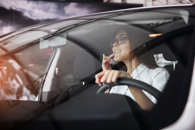 Hübsche junge Frau, die neues Auto fährt.