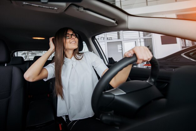 Hübsche junge Frau, die neues Auto fährt.