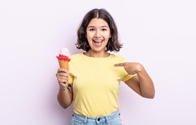 Hübsche junge Frau, die sich glücklich fühlt und mit einem aufgeregten Eiskonzept auf sich selbst zeigt