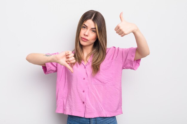 Hübsche junge Frau, die sich verwirrt, ahnungslos und unsicher fühlt, wenn sie das Gute und das Schlechte in verschiedenen Optionen oder Entscheidungen gewichtet