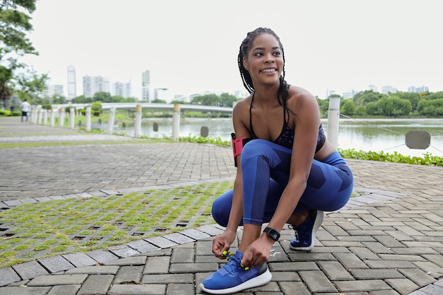 Hübsche junge Frau gemischter Abstammung, die Schnürsenkel bindet und sich für das lange Morgenjoggen bereit macht