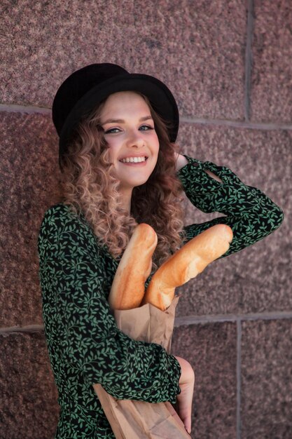 Hübsche junge Frau im französischen Stil mit Baguettes in den Händen