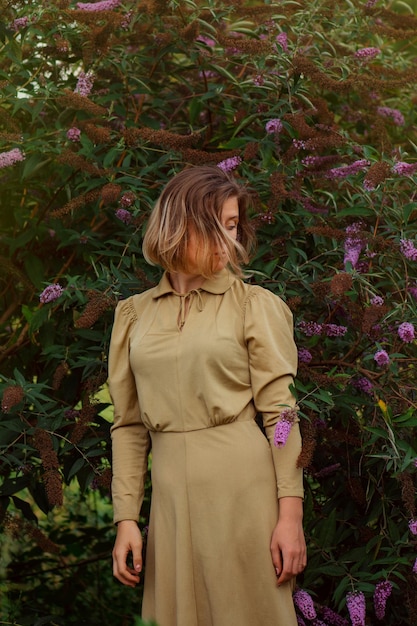 Hübsche junge Frau im goldenen Kleid auf Sommerflieder Weizenfeld Porträt der zarten Frau auf einem Feld