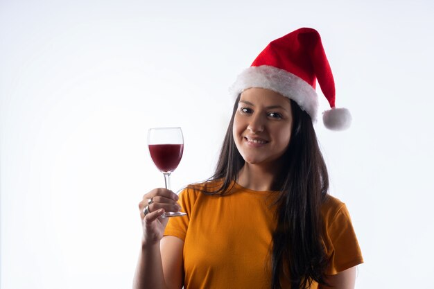 Hübsche junge Frau in einem Weihnachtsmann-Hut, mit einem Glas Wein. weißer Hintergrund