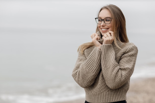 hübsche junge frau in kuscheliger kleidung am meer