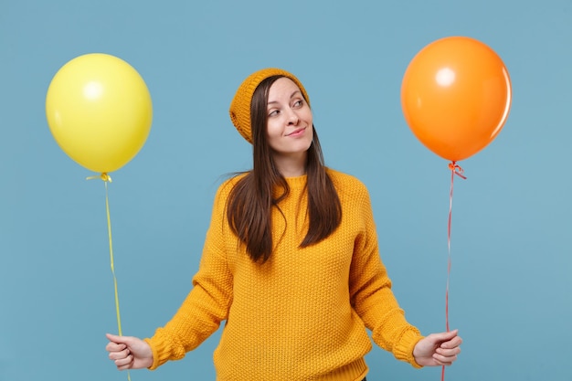 Hübsche junge Frau Mädchen in Pullover Hut posiert isoliert auf blauem Hintergrund Studioportrait. Geburtstagsfeier, Menschen Emotionen Konzept. Mock-up-Kopienbereich. Feiern halten bunte Luftballons.