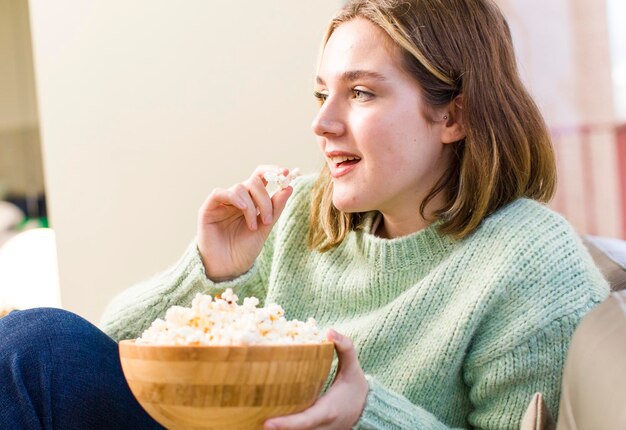 Hübsche junge Frau mit einem Popcorn-Schüssel-Haus Innenarchitektur